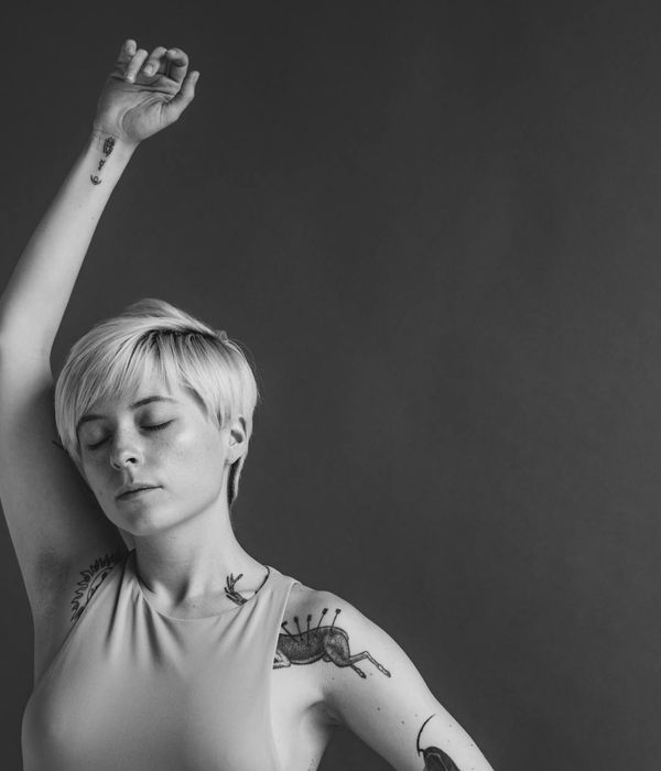 Person stretching gracefully in a minimalist studio with soft lighting.